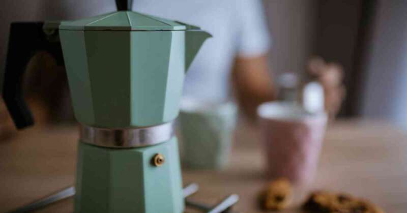 Moka pot on a table with cookies.