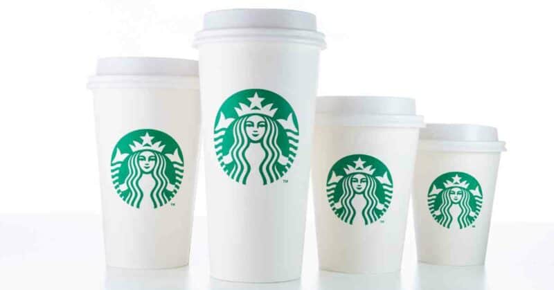 Various sizes of Starbucks coffee cups on a white table.