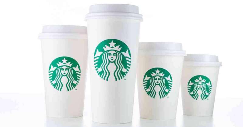 Various sizes of Starbucks coffee cups on a white table.